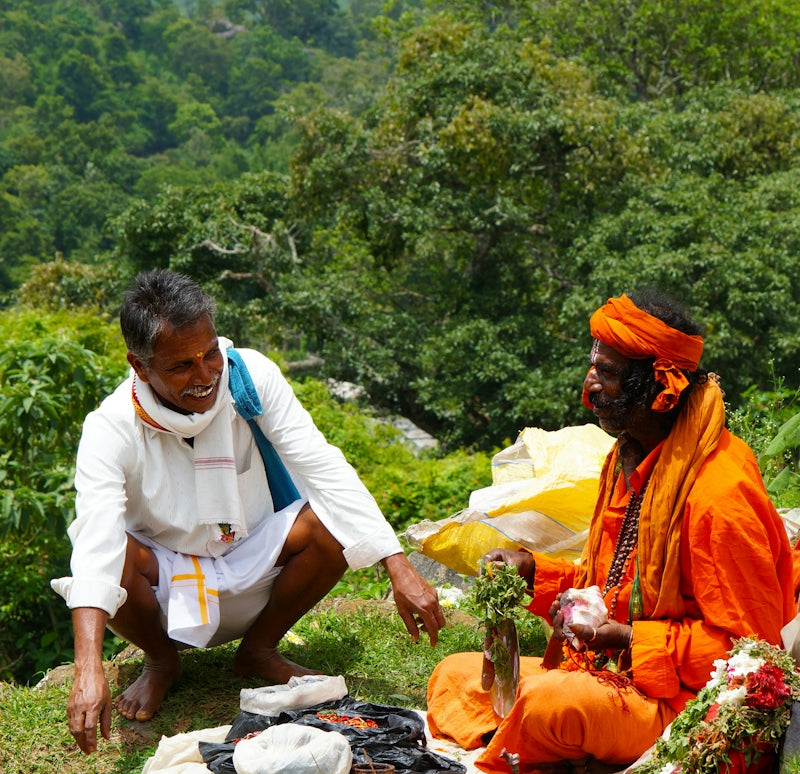 a couple of men sitting on top of a lush green field